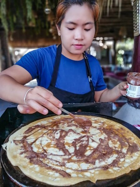 Jeune cuisinière thaïlandaise cuisinant une grande crêpe au chocolat et noisette a La Bohemia a Koh Samui